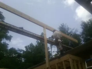 Carpenter setting a ridge beam over a new addition frame — Ice Dam Removal by Roofing Brothers in Pell City