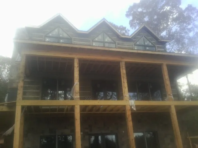Dormers and porch framing on a large log home under construction — Roof Coating work by our crew in Pell City