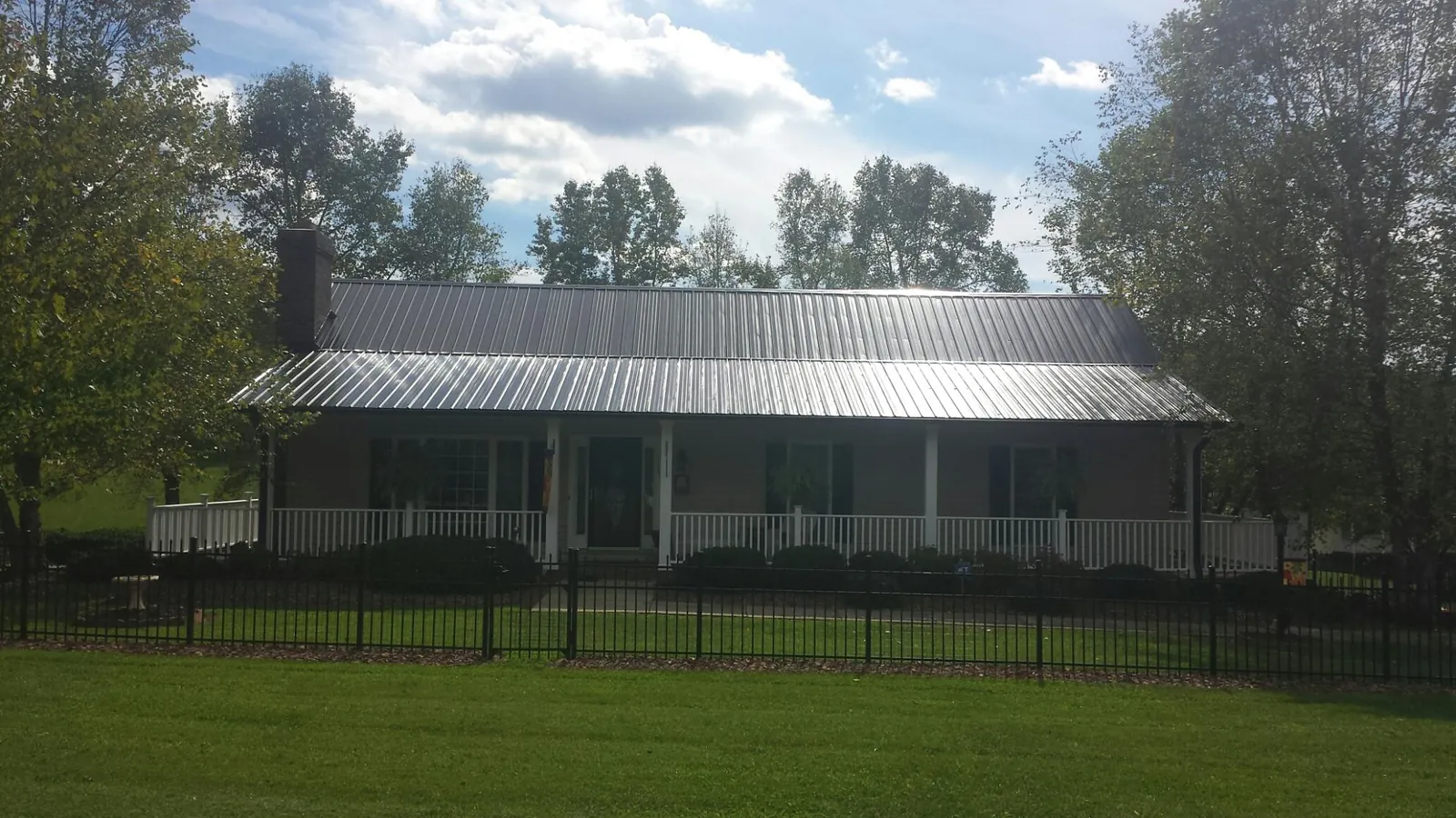 Gray metal roof on a brick ranch with a full width front porch — Gutter Guard Installation work by our crew in Pell City