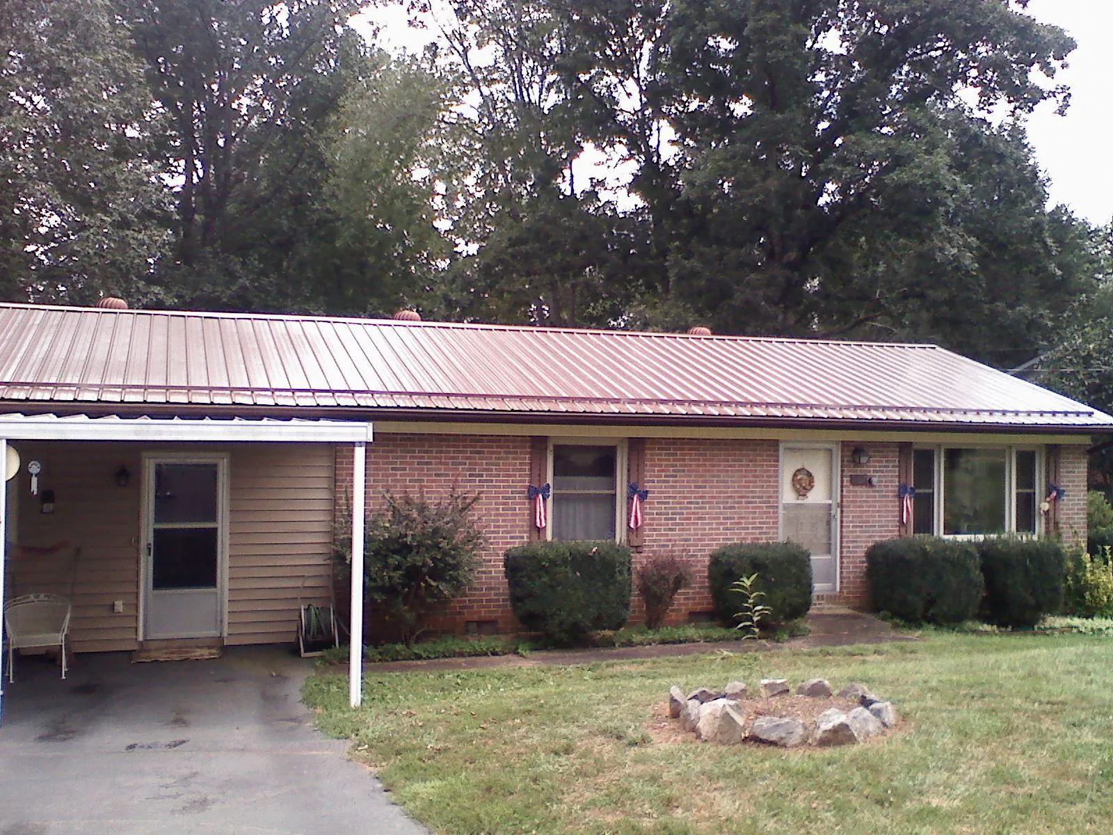 Bronze metal roof and carport on a brick ranch home — Roof Repair work by our crew in Pell City