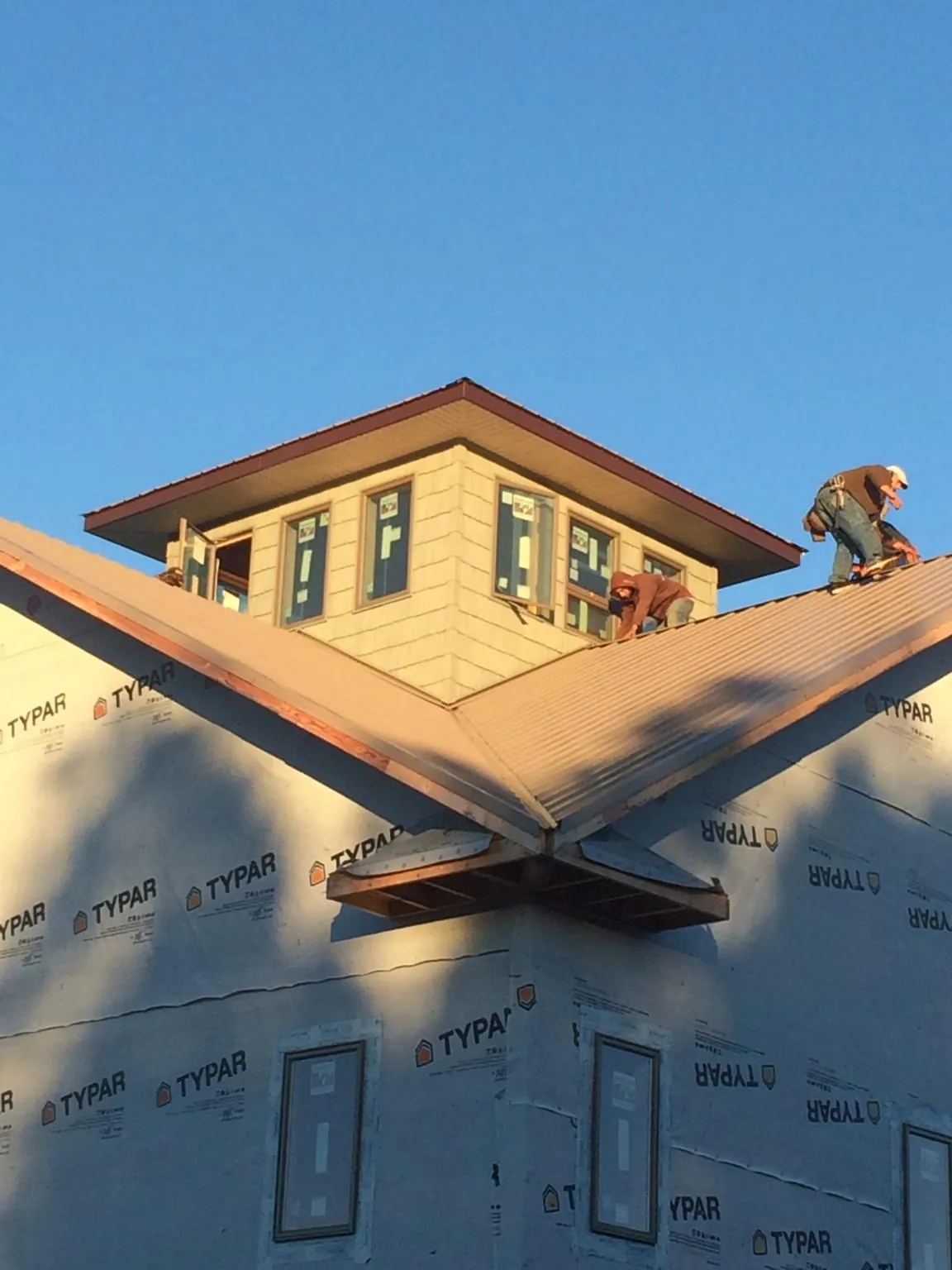 Roofers working around a rooftop cupola on a new metal roof at sunset — Roof Waterproofing in Pell City by Roofing Brothers
